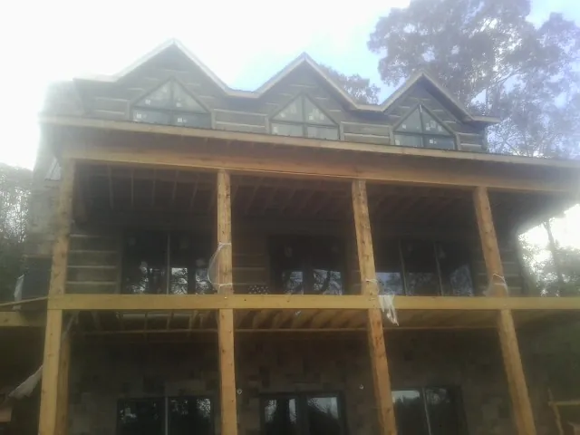 Dormers and porch framing on a large log home under construction — Roof Coating work by our crew in Altamahaw
