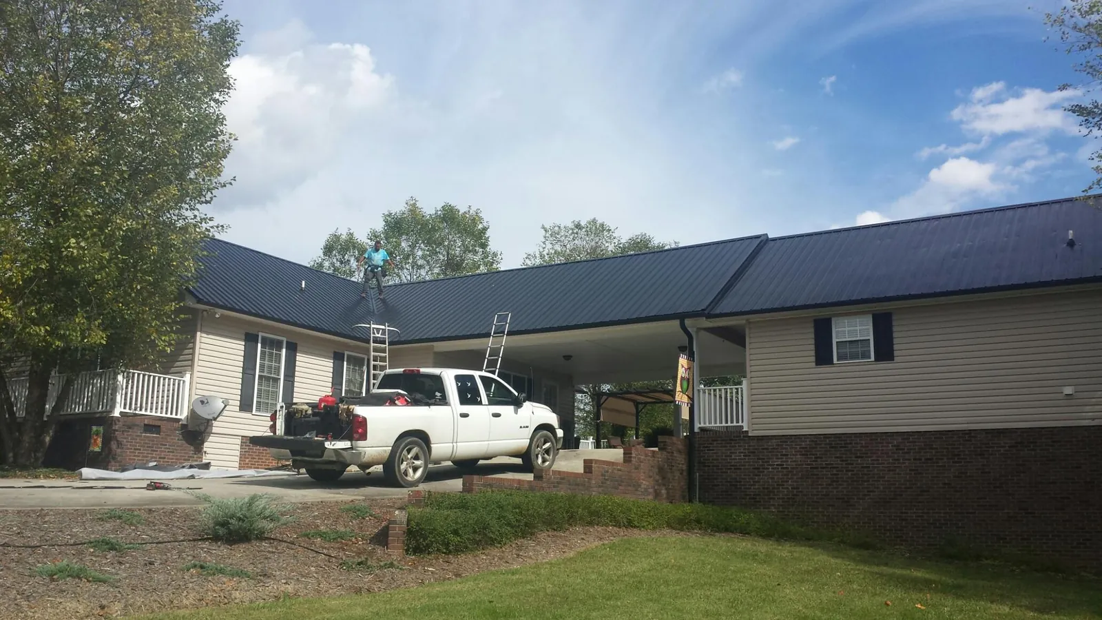 Black metal roof over a home and attached breezeway with ladders set in Altamahaw