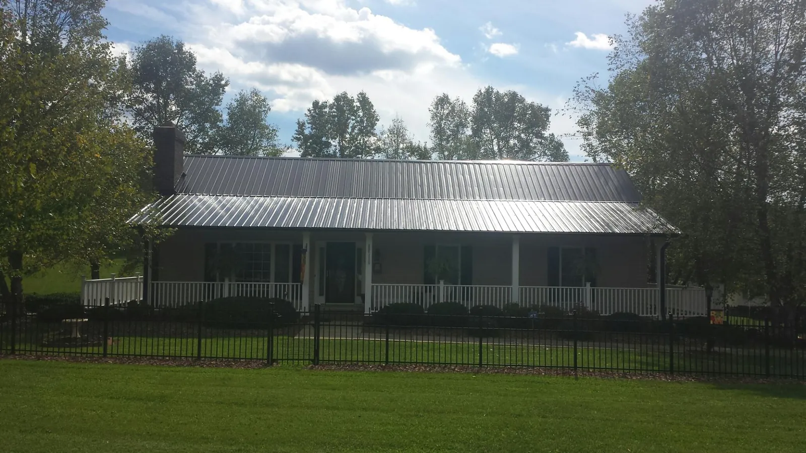Gray metal roof on a brick ranch with a full width front porch — Gutter Guard Installation work by our crew in Altamahaw
