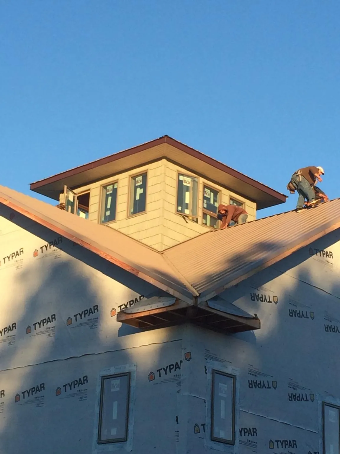 Roofers working around a rooftop cupola on a new metal roof at sunset — Roof Waterproofing in Altamahaw by Roofing Brothers